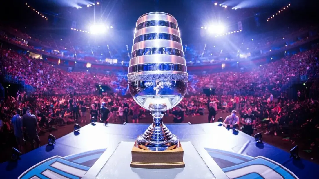 A championship trophy on stage in front of a packed esports arena